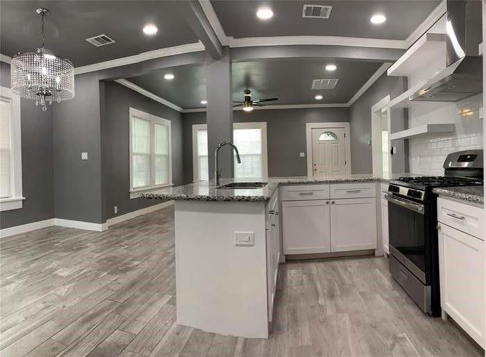 Open-plan kitchen with a white island, granite countertops, and stainless steel range.