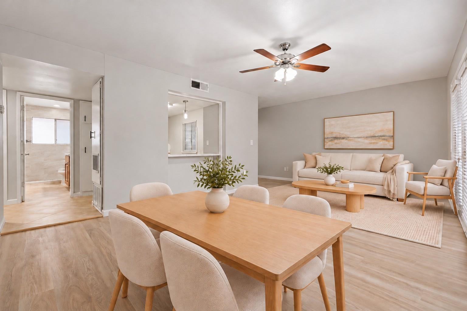 Open-plan living and dining room with a cream sofa, wooden dining table, and ceiling fan.