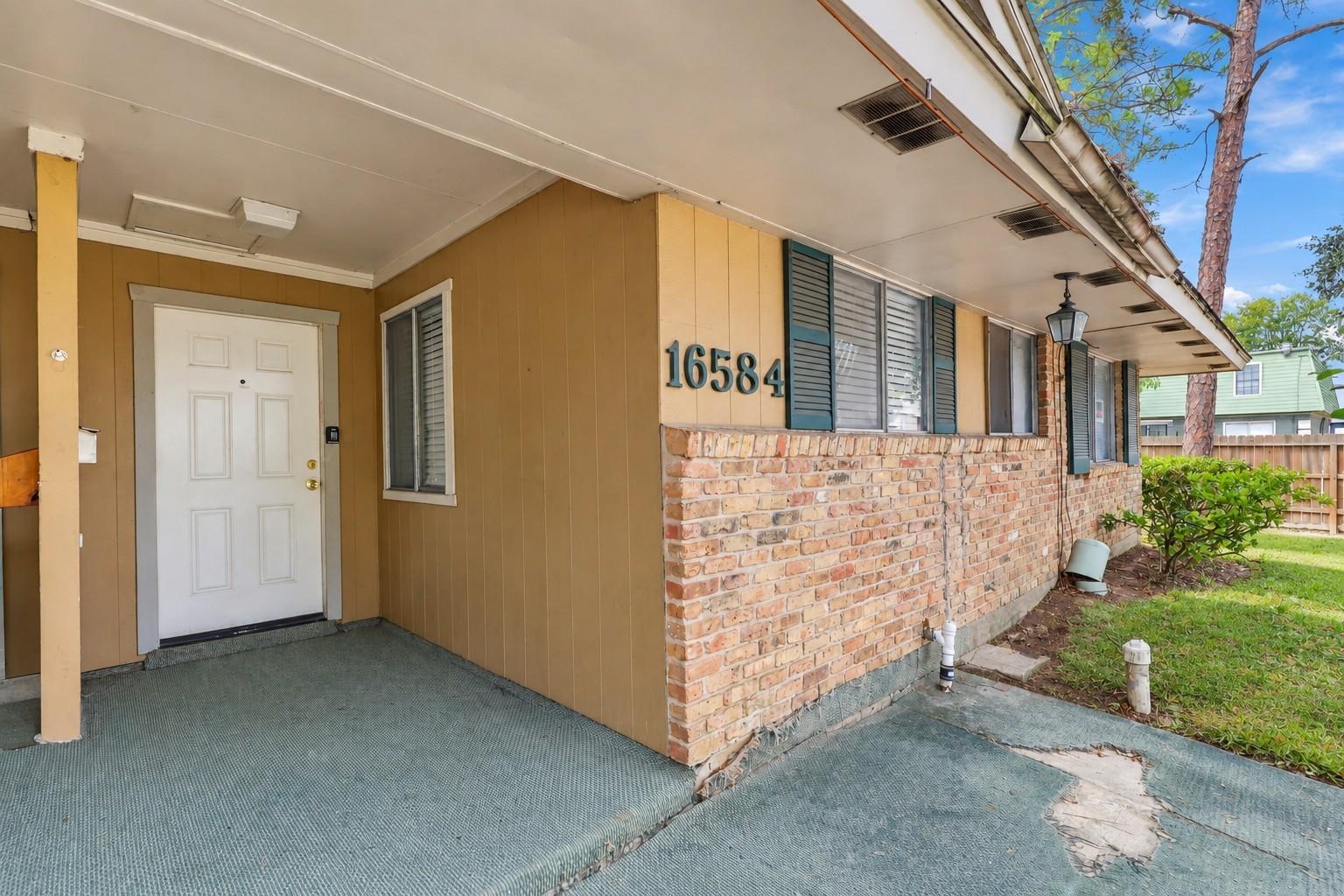 Home entrance with a white door, brick facade, and the number 16584.