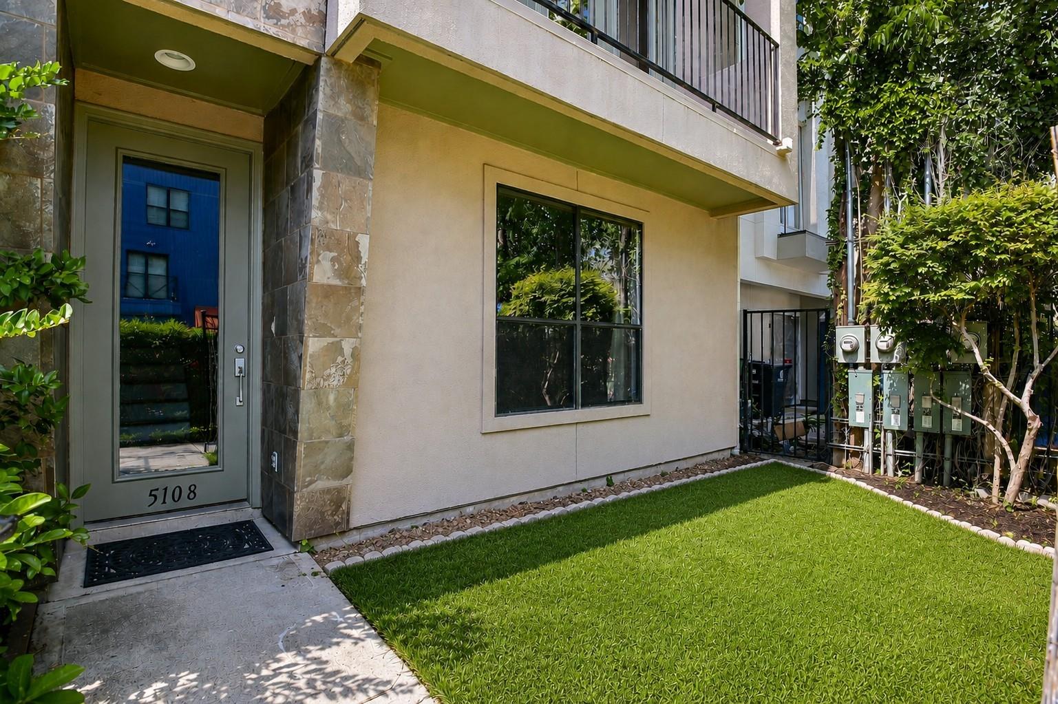 Home entrance marked 5108 beside a small lawn, with a covered entry and upper balcony.