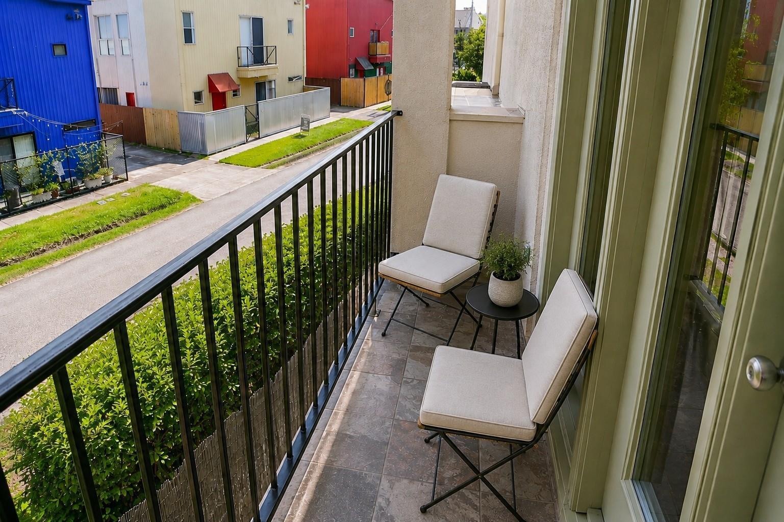 Furnished balcony with tiled floor and chairs overlooking colorful townhouses