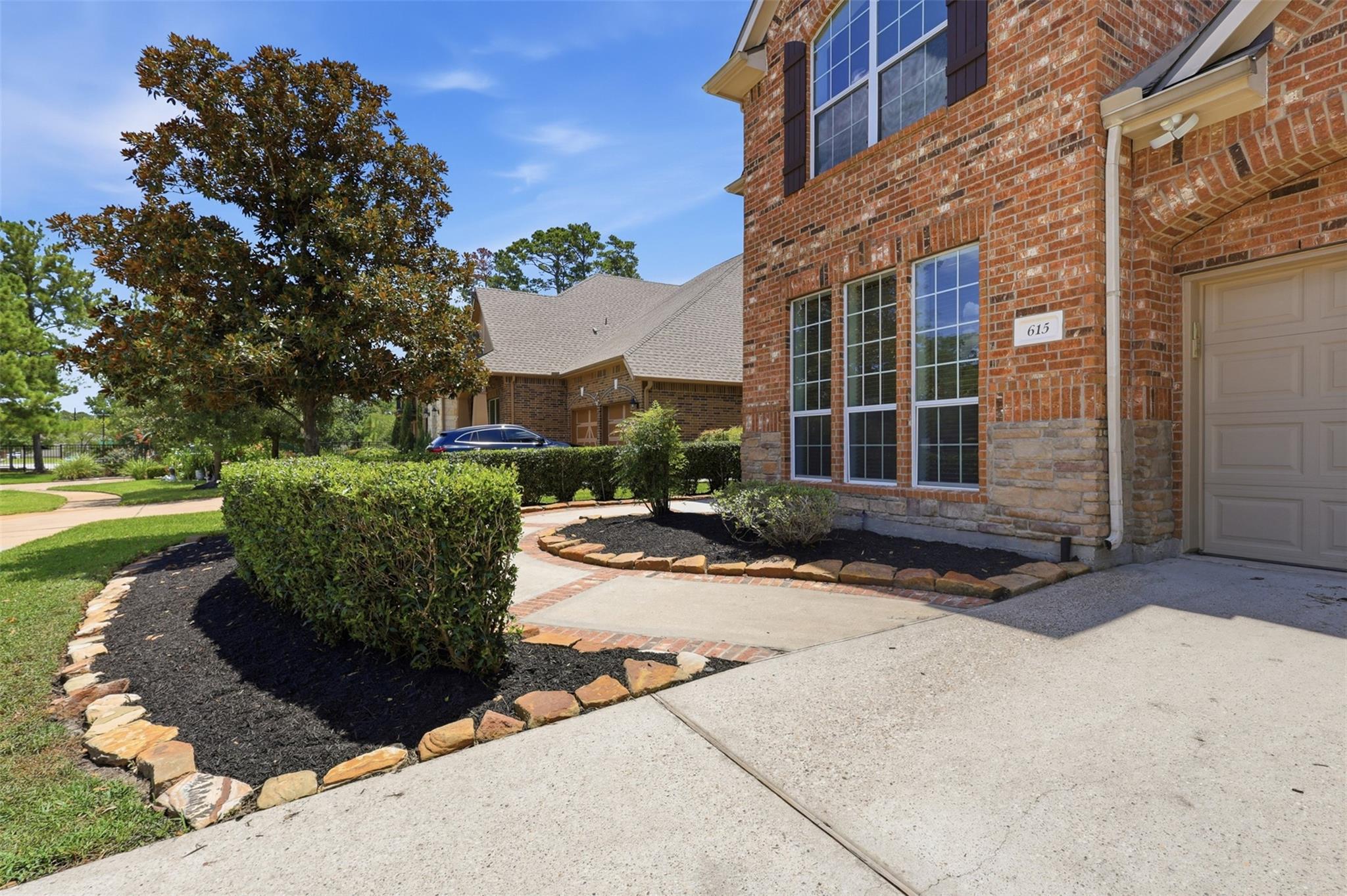 Brick home with tall windows, attached garage, and landscaped walkway; house number 615 beside the entry.