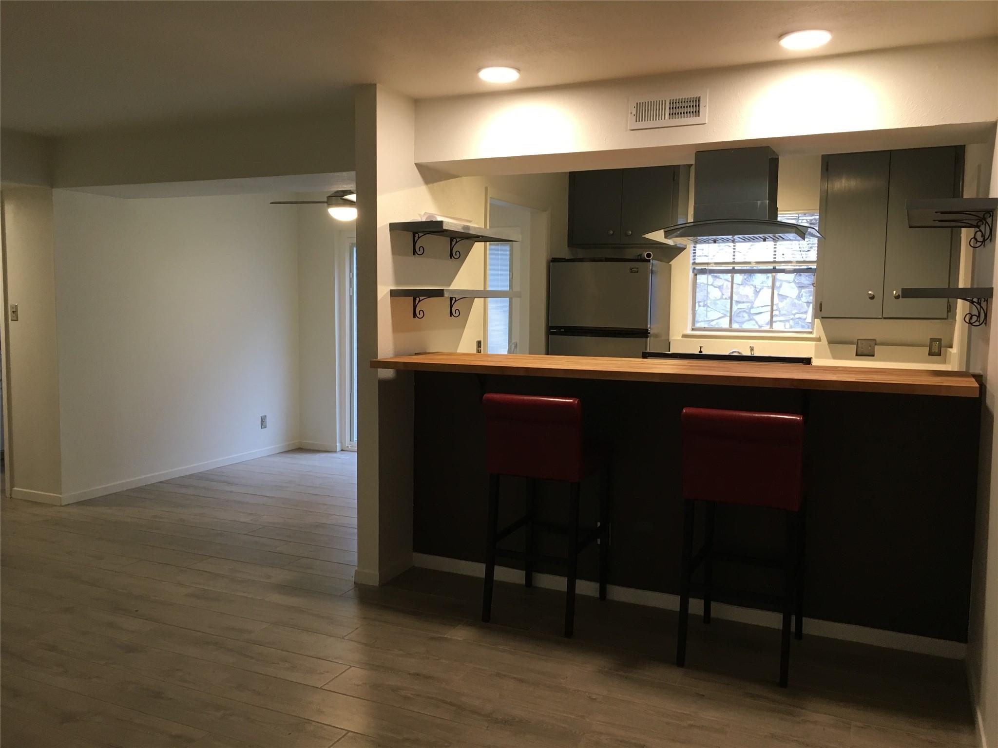 Kitchen with dark cabinets, a long wood breakfast bar, and two red stools.