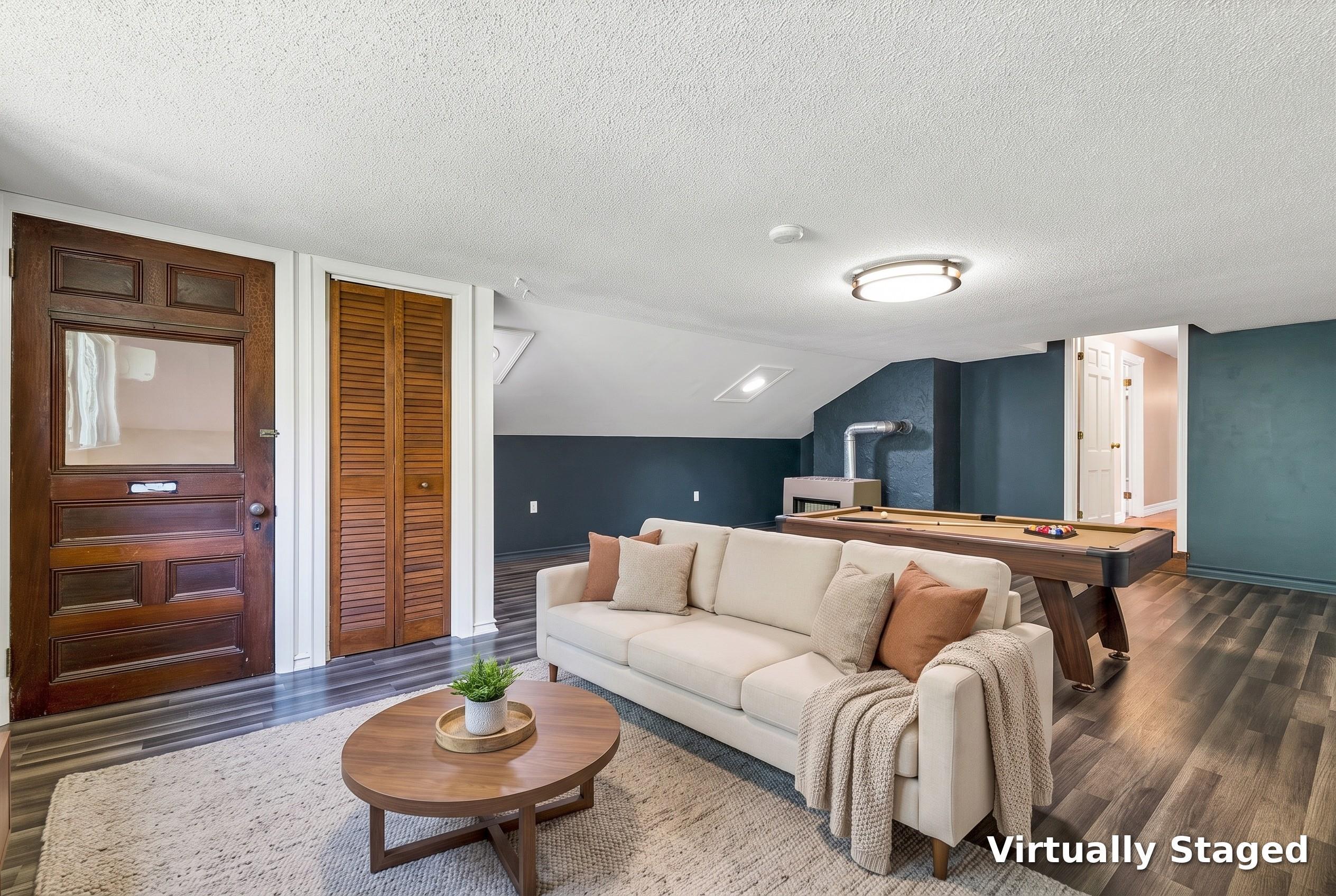 Basement recreation room with a cream sofa, round coffee table, and pool table against dark blue walls.