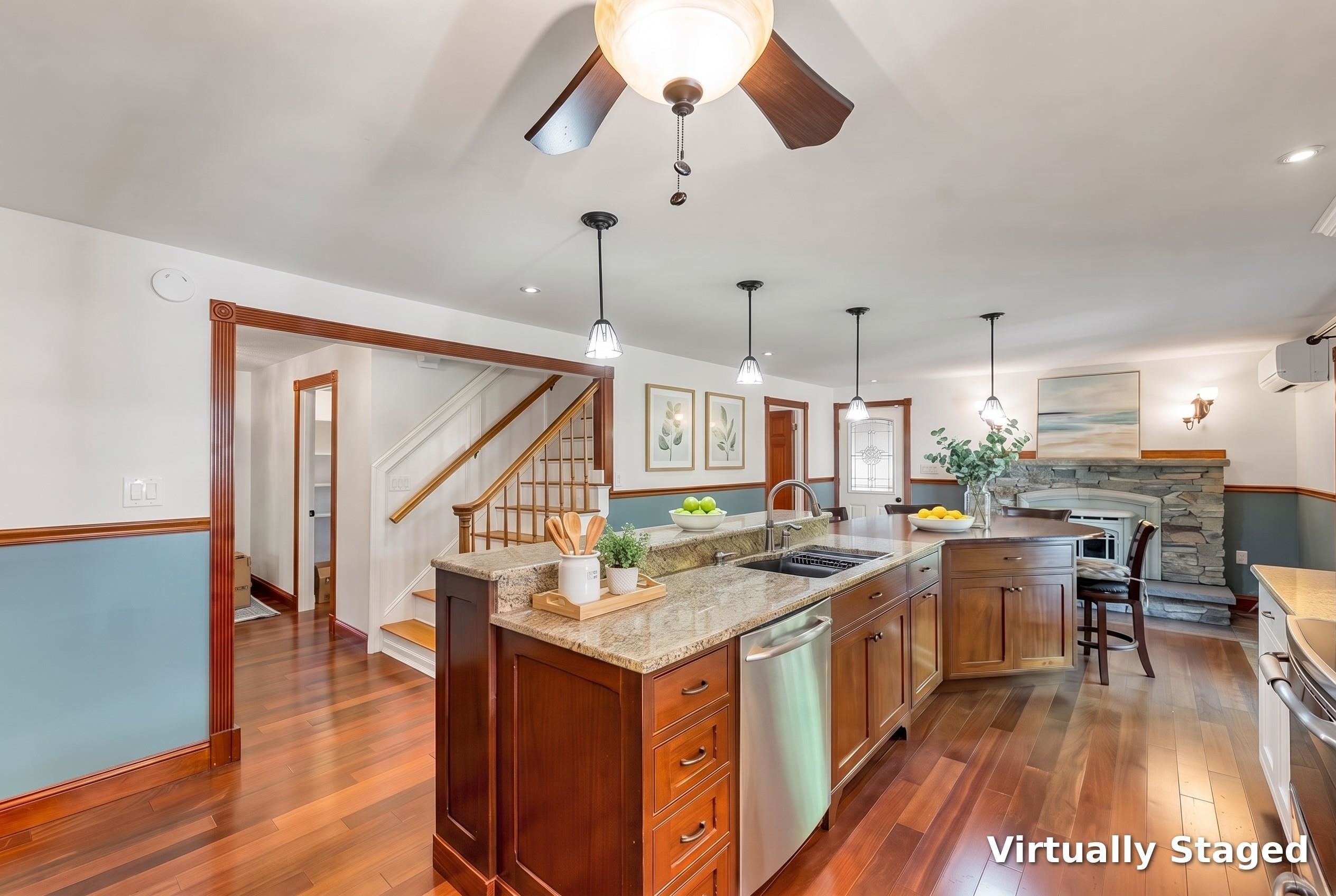 Kitchen with a granite island, dark wood cabinets, hardwood floors, and a stone fireplace.