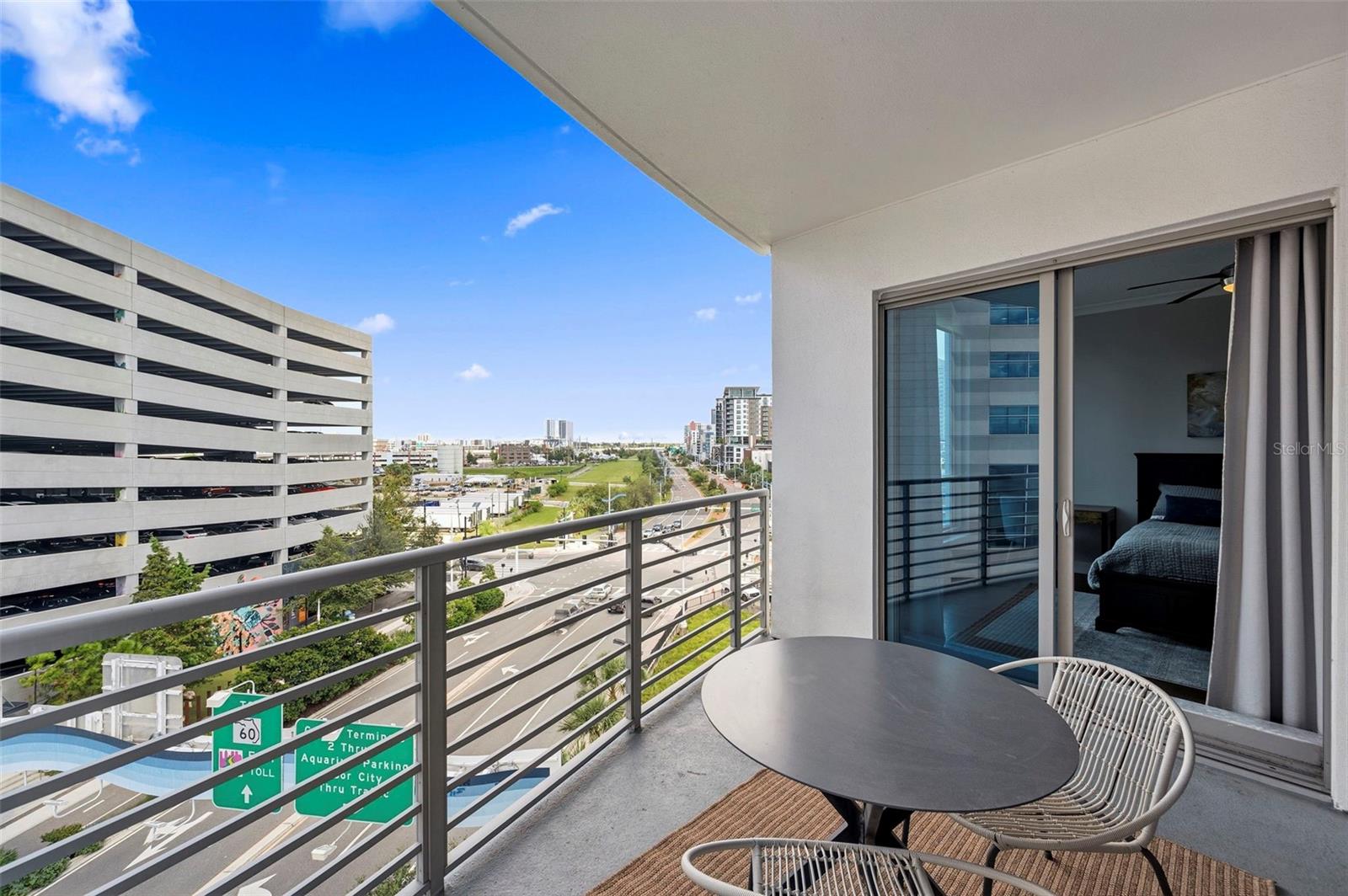 Condo balcony with outdoor seating overlooking a Tampa street and nearby buildings.