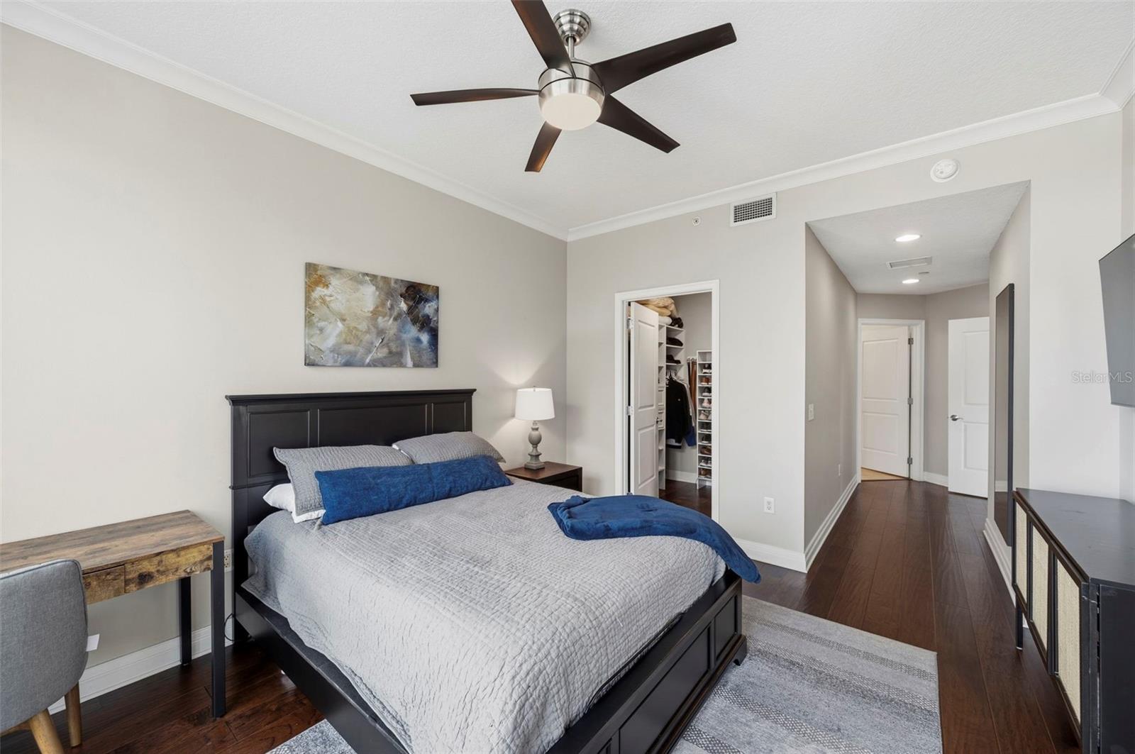 Bedroom with a dark wood bed, blue and gray bedding, ceiling fan, and open closet.