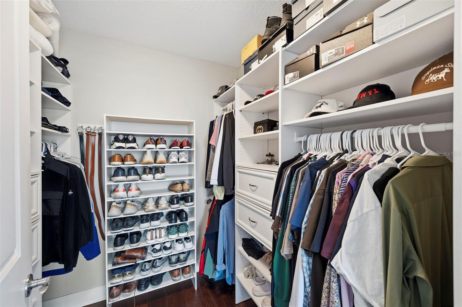Walk-in closet with built-in shelving, rows of shoes, drawers, and hanging clothes.