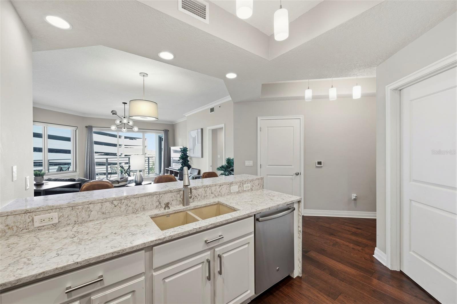 Condo kitchen with a stone breakfast bar opening onto a furnished living area.