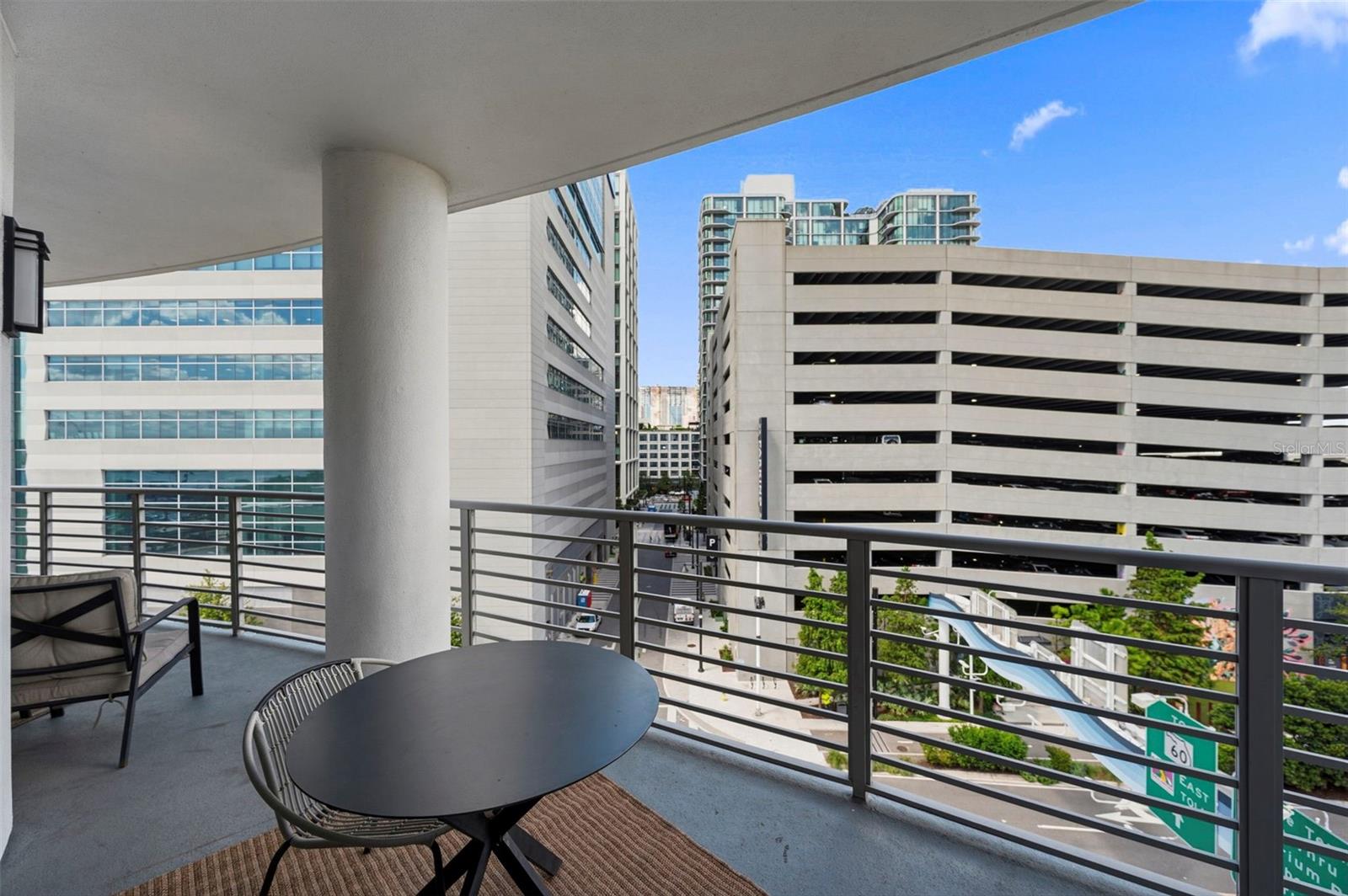 Condominium balcony with outdoor dining set overlooking downtown buildings and streets.