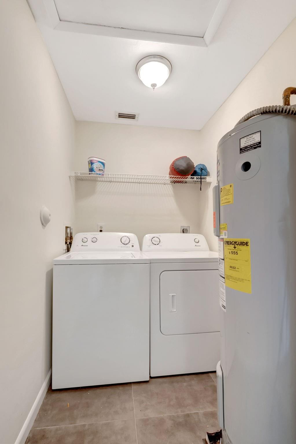 Laundry room with a washer, dryer, wire shelf, and large water heater.