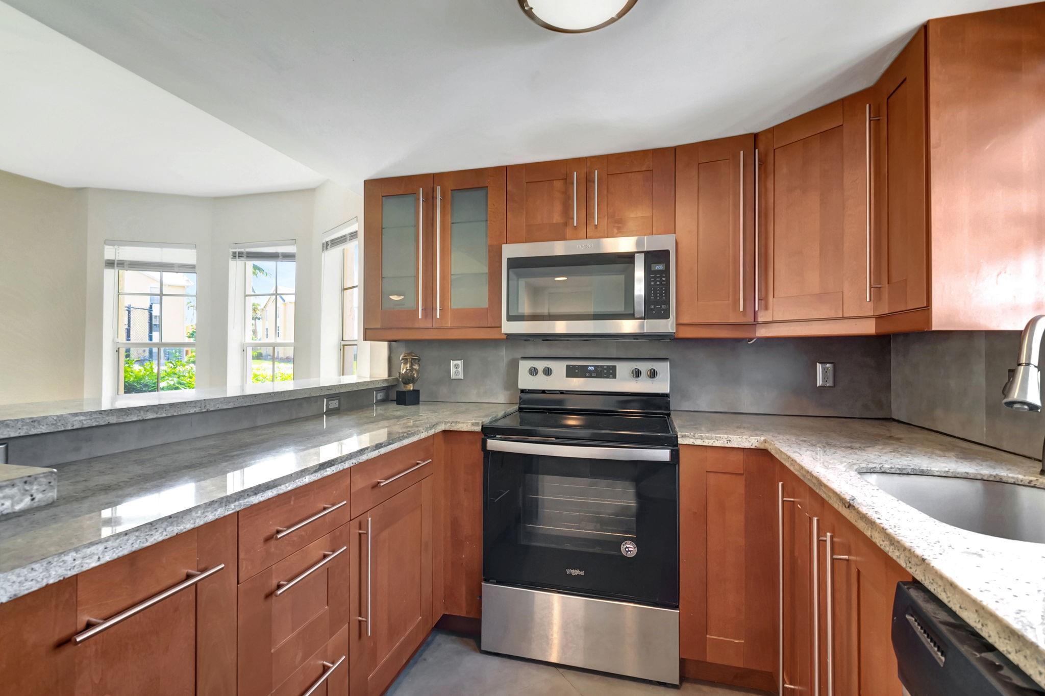 Kitchen with reddish-brown cabinets, gray stone counters, and stainless steel appliances.