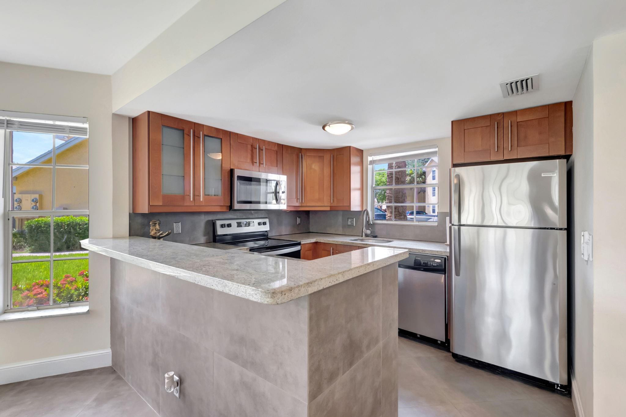 Kitchen with wood cabinets, stainless steel appliances, and a large stone peninsula.