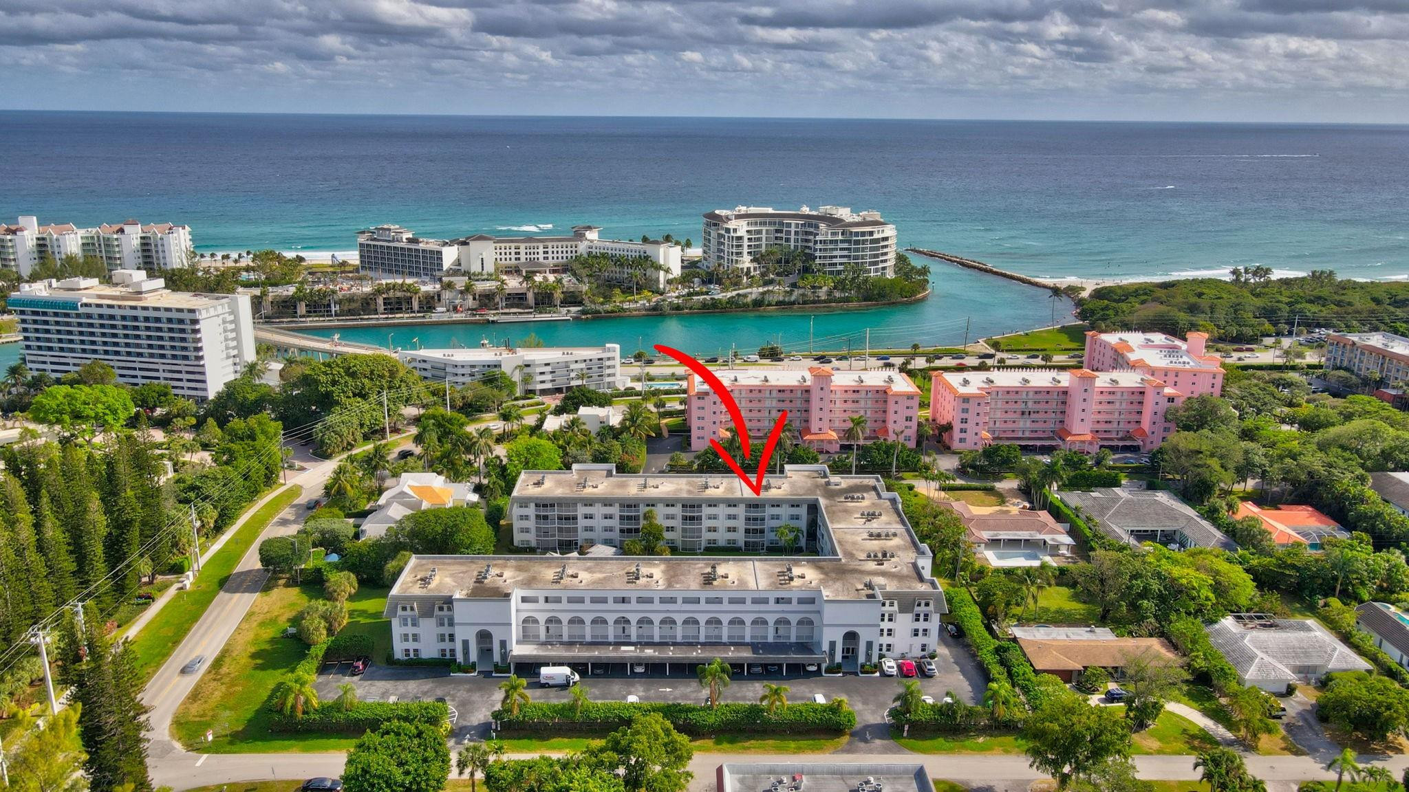 Aerial view of the condominium marked by a red arrow, with the inlet and ocean behind it.
