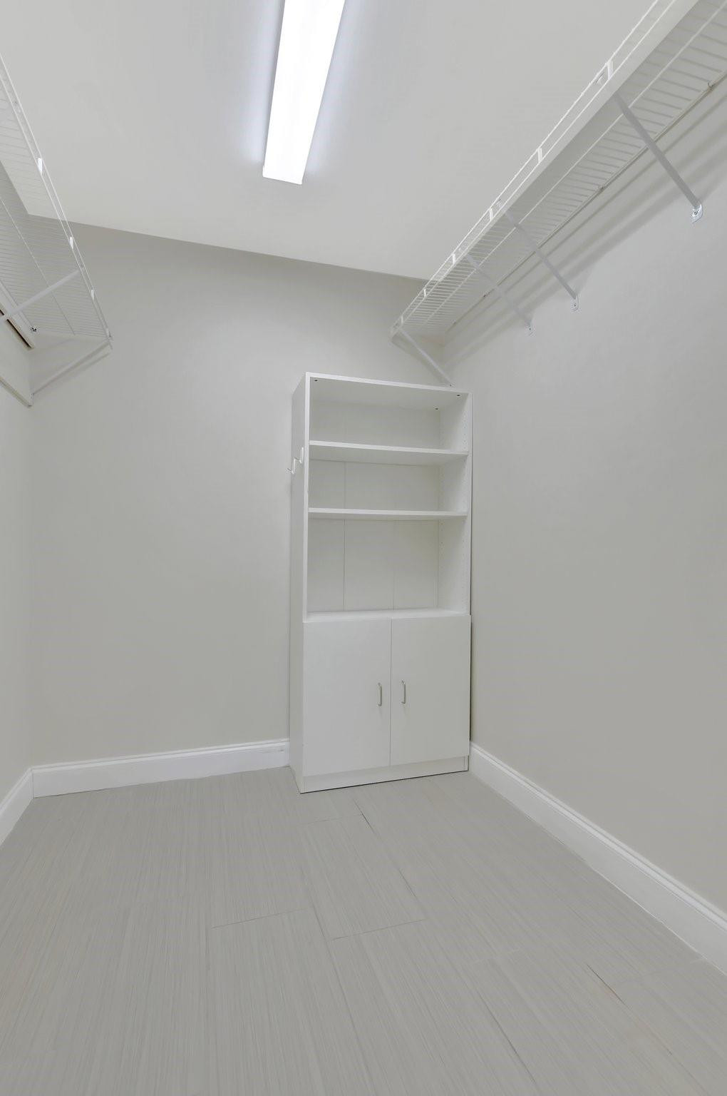 Walk-in closet with white wire shelving and a built-in cabinet with open shelves and doors.
