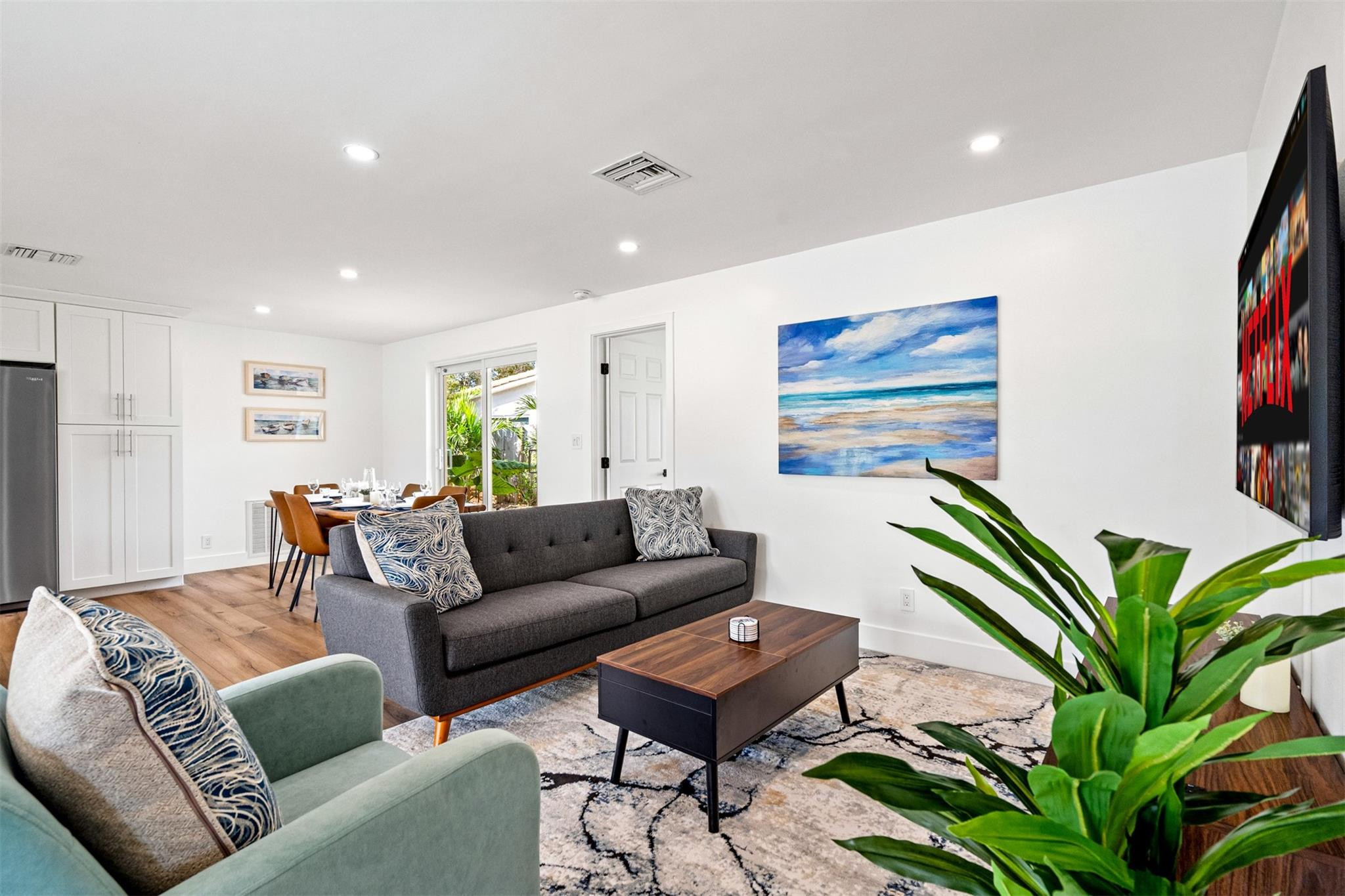 Staged living room with a dark gray sofa, wood coffee table, and sliding doors overlooking greenery.