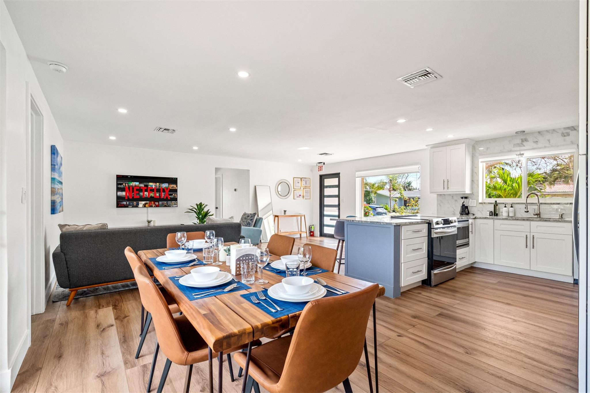 Open-plan kitchen, dining, and living area with a blue island and a set dining table.