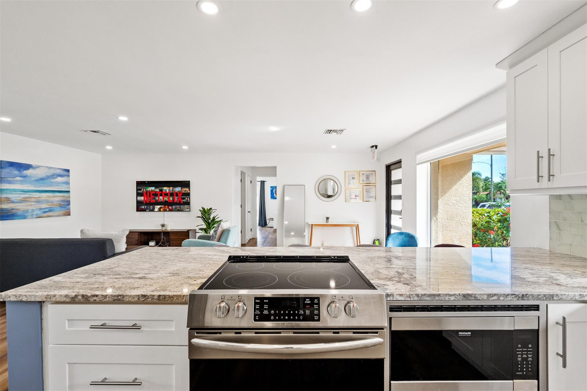 Kitchen with a granite island and stainless-steel range, opening onto a living room.