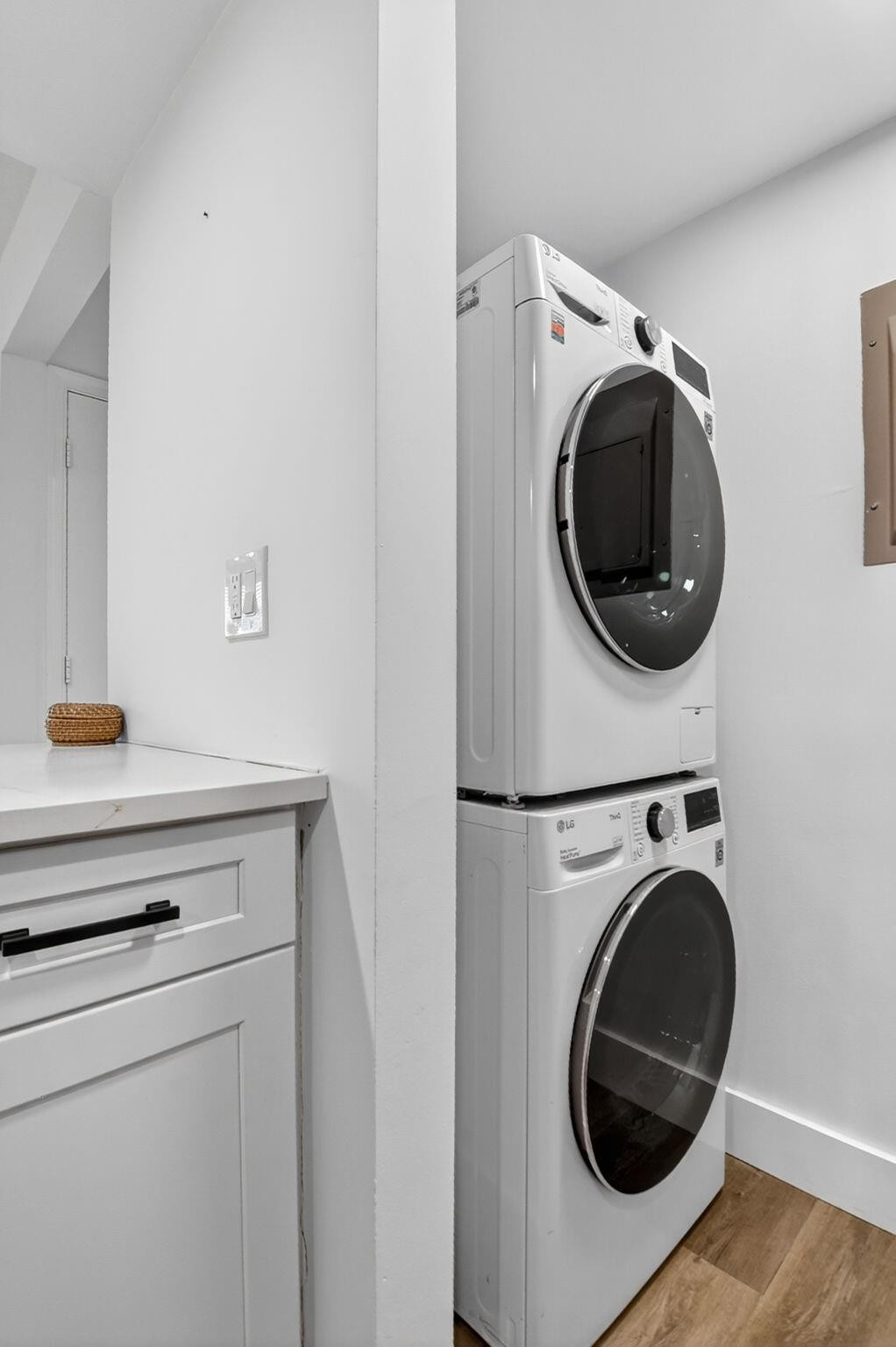 Laundry area with stacked white washer and dryer beside built-in cabinetry and a countertop.
