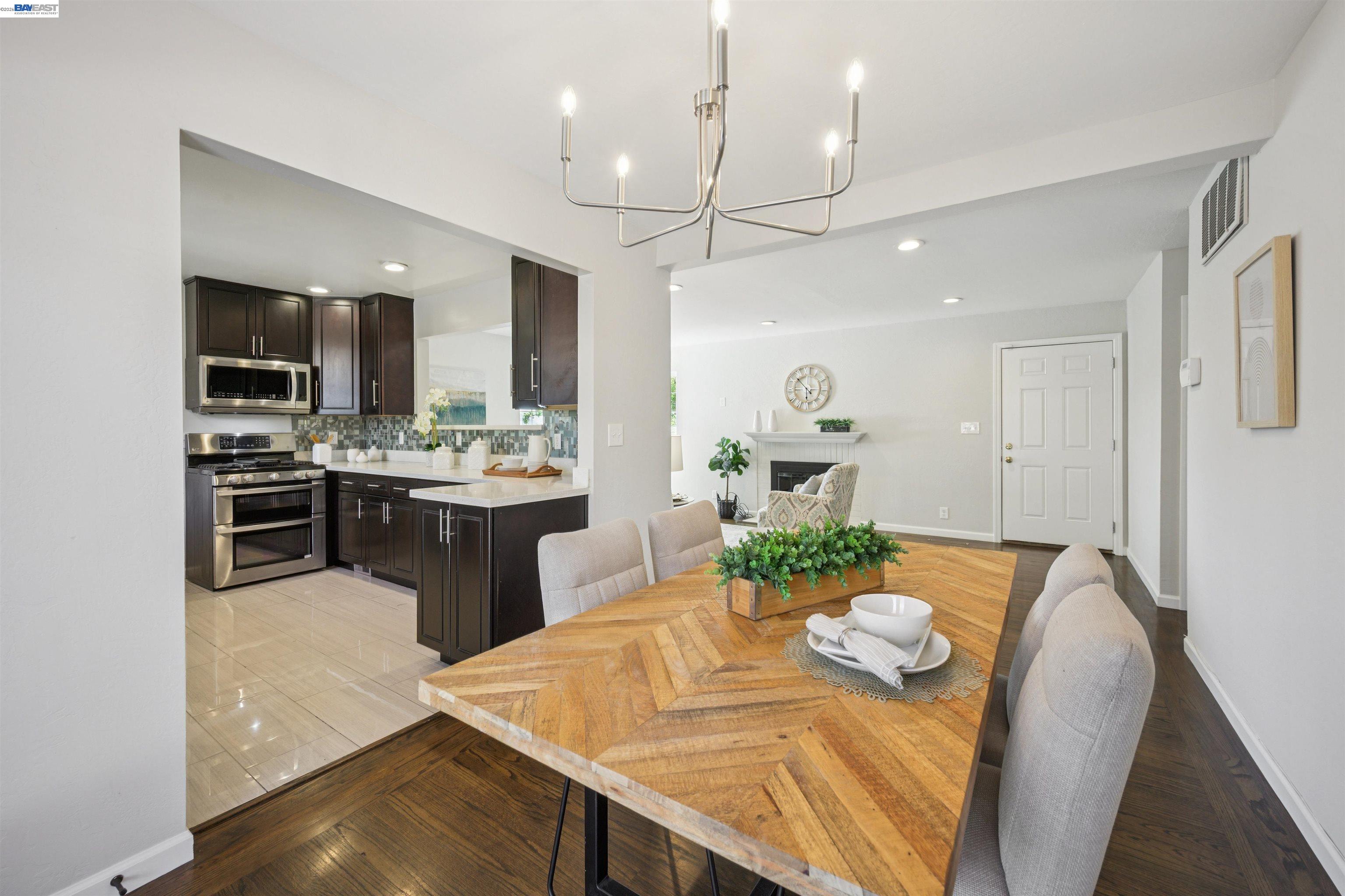Open-plan dining room and kitchen with a geometric wood table and dark cabinetry.