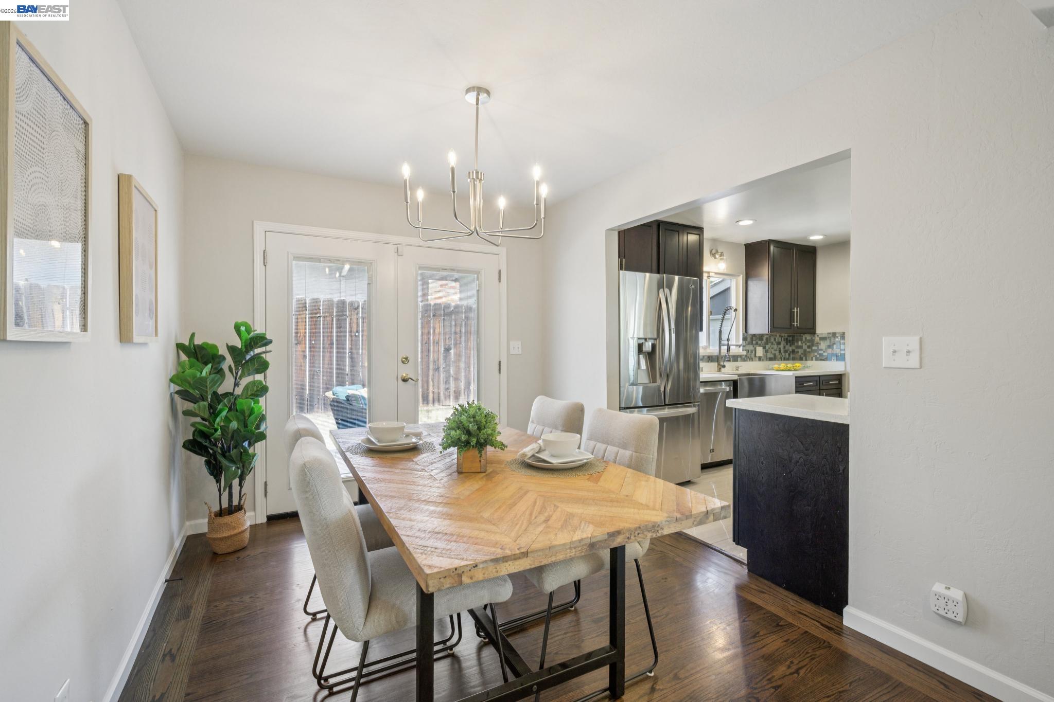 Dining area with a light wood table and upholstered chairs beside a modern kitchen.