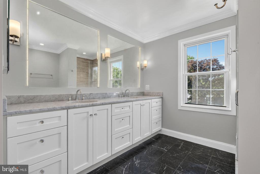 Bathroom with a long white double vanity, marble-look countertop, and large mirrors.