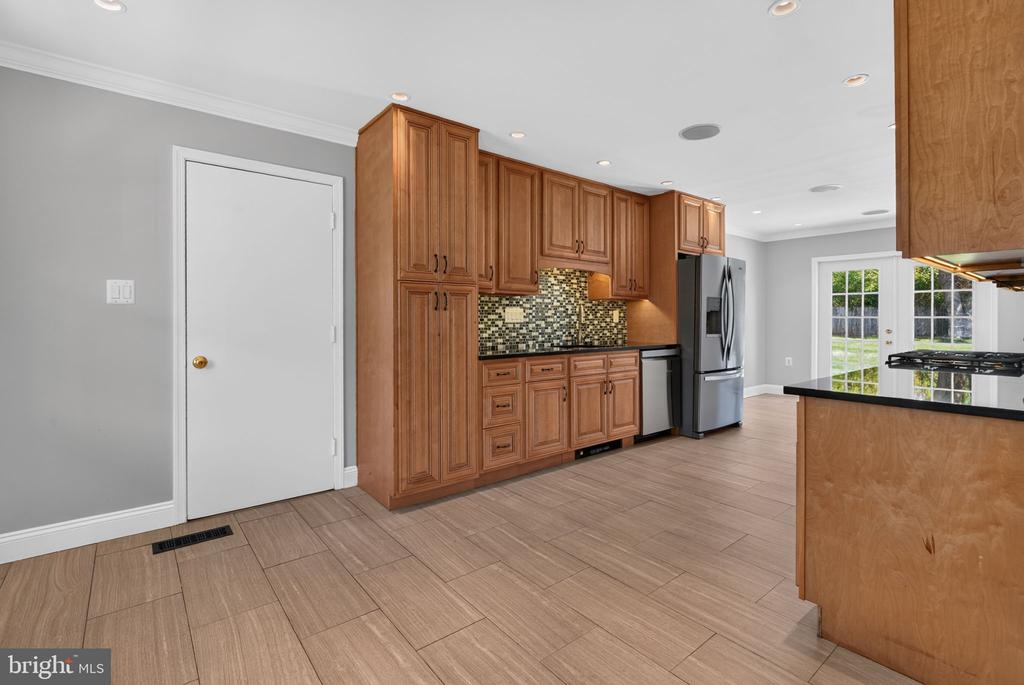 Kitchen with warm wood cabinets, mosaic backsplash, stainless steel appliances, and French doors.