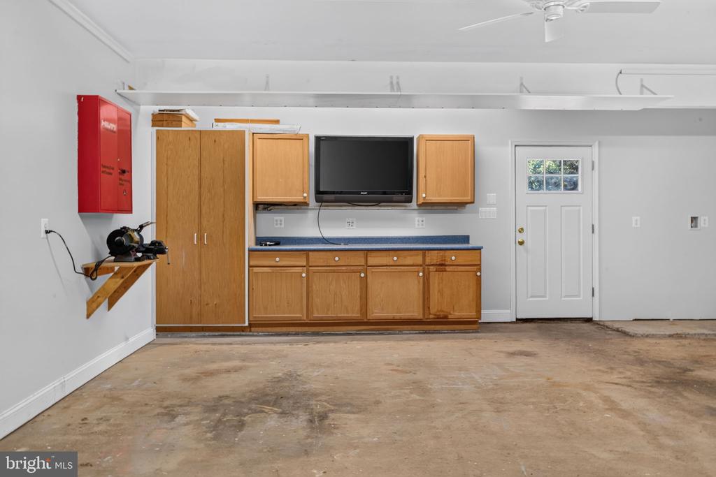 Garage with built-in wooden cabinets, a concrete floor, and a wall-mounted television.
