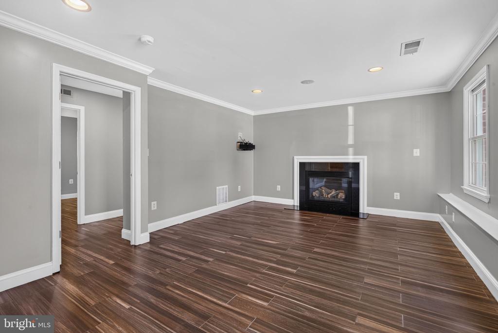 Empty living room with dark plank flooring, gray walls, and a gas fireplace.