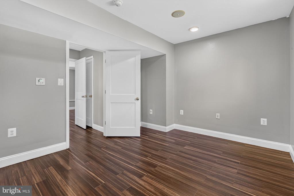 Empty room with dark wood-look flooring, gray walls, and open white doors.
