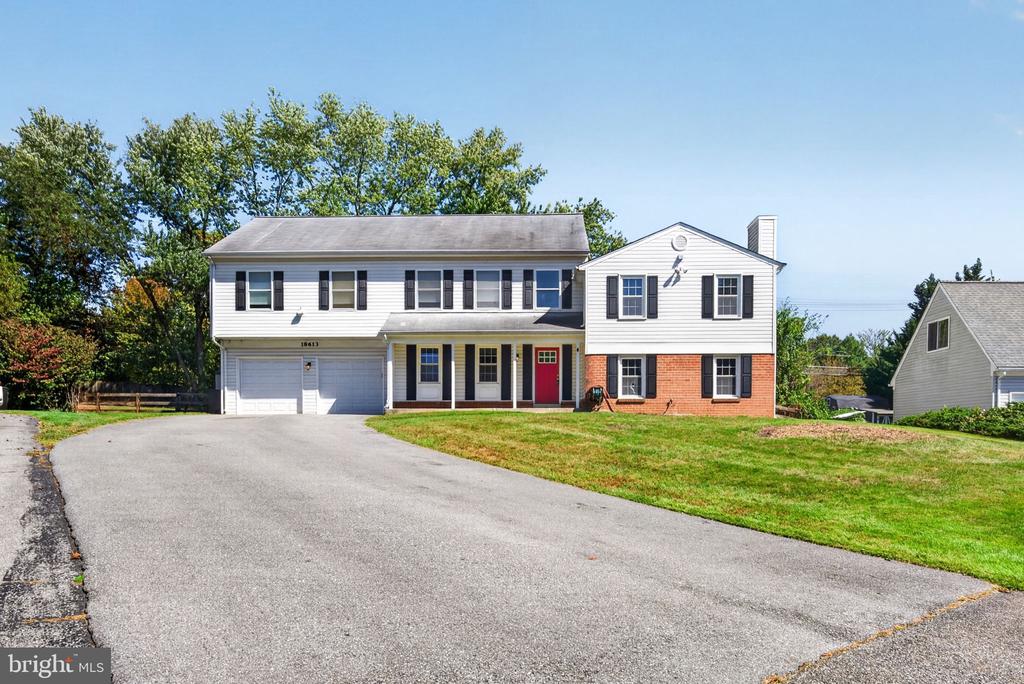 Two-story white-sided home with brick lower facade, red front door, and attached two-car garage.