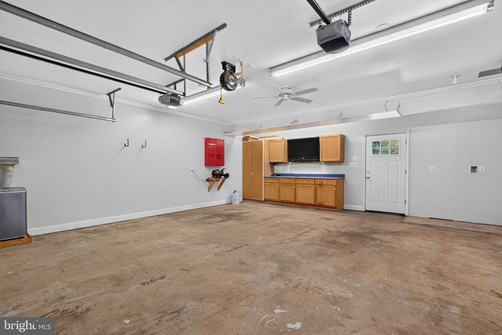 Empty garage with overhead door tracks and wooden cabinets along the back wall.