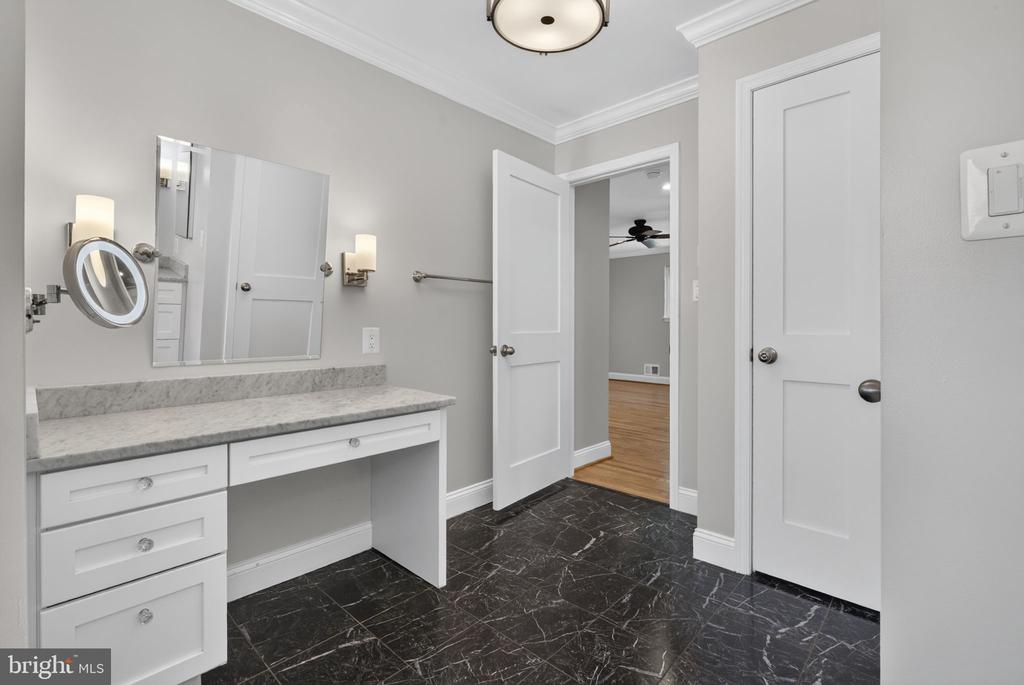 Bathroom with a white vanity, large mirror, and glossy black veined tile floor.