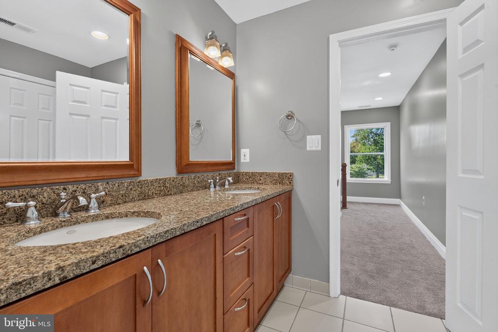 Bathroom with a double-sink granite vanity and an open doorway to a carpeted room.