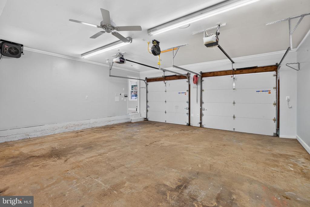 Empty two-car garage with two overhead doors and a ceiling fan.