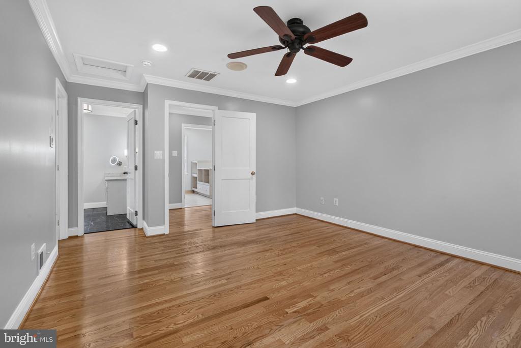 Unfurnished room with hardwood floors, gray walls, and a dark wood ceiling fan.