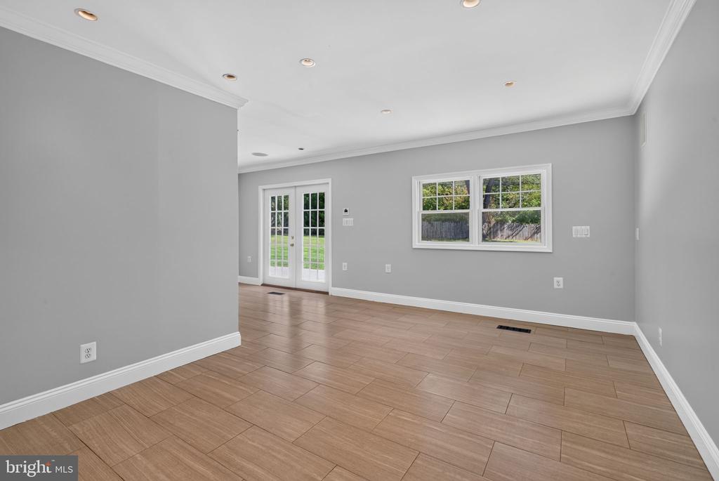 Empty living area with gray walls, recessed lights, tile flooring, and glass doors opening to a lawn.