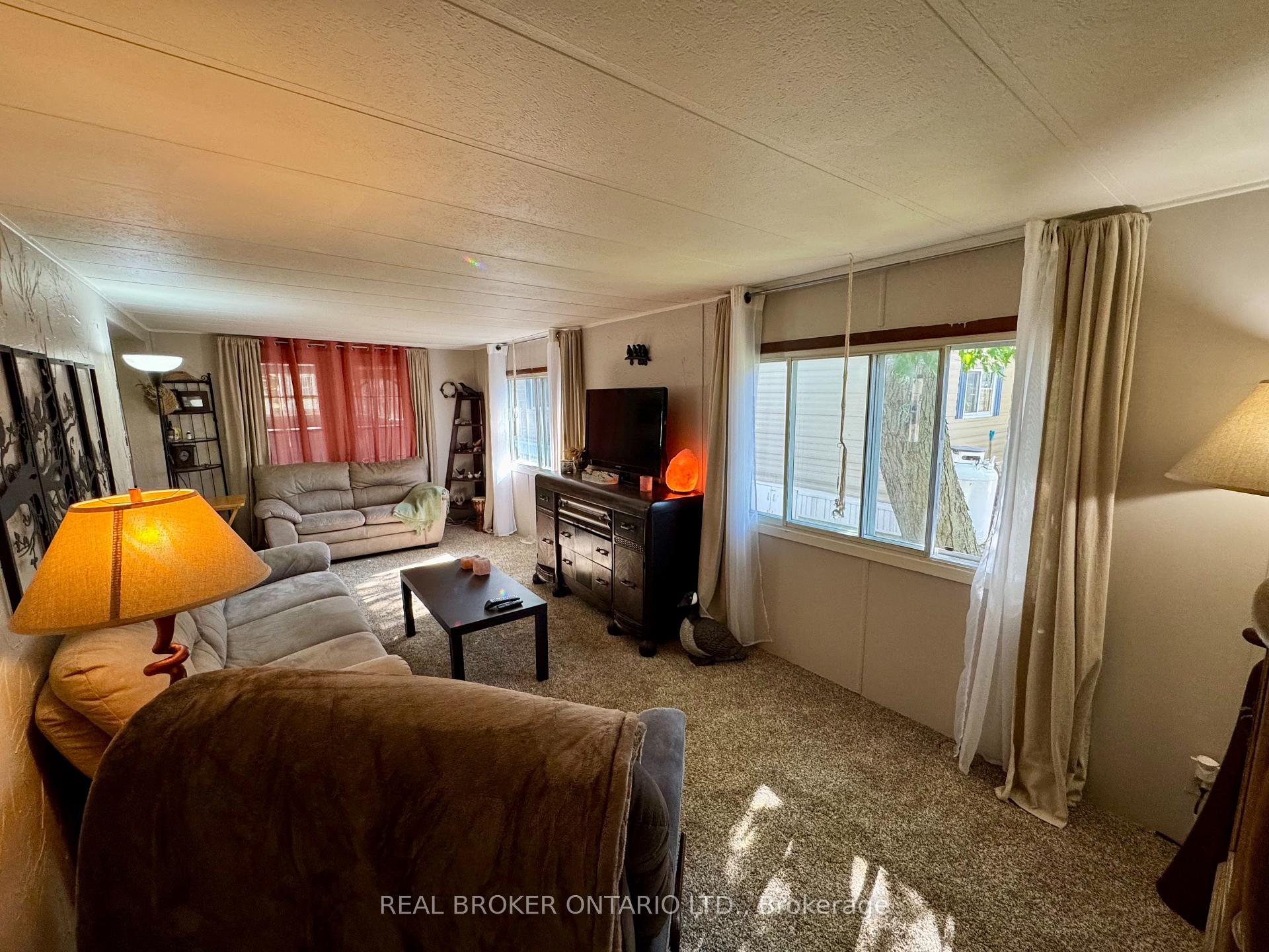 Living room with gray sofas, a television, and large curtained windows.