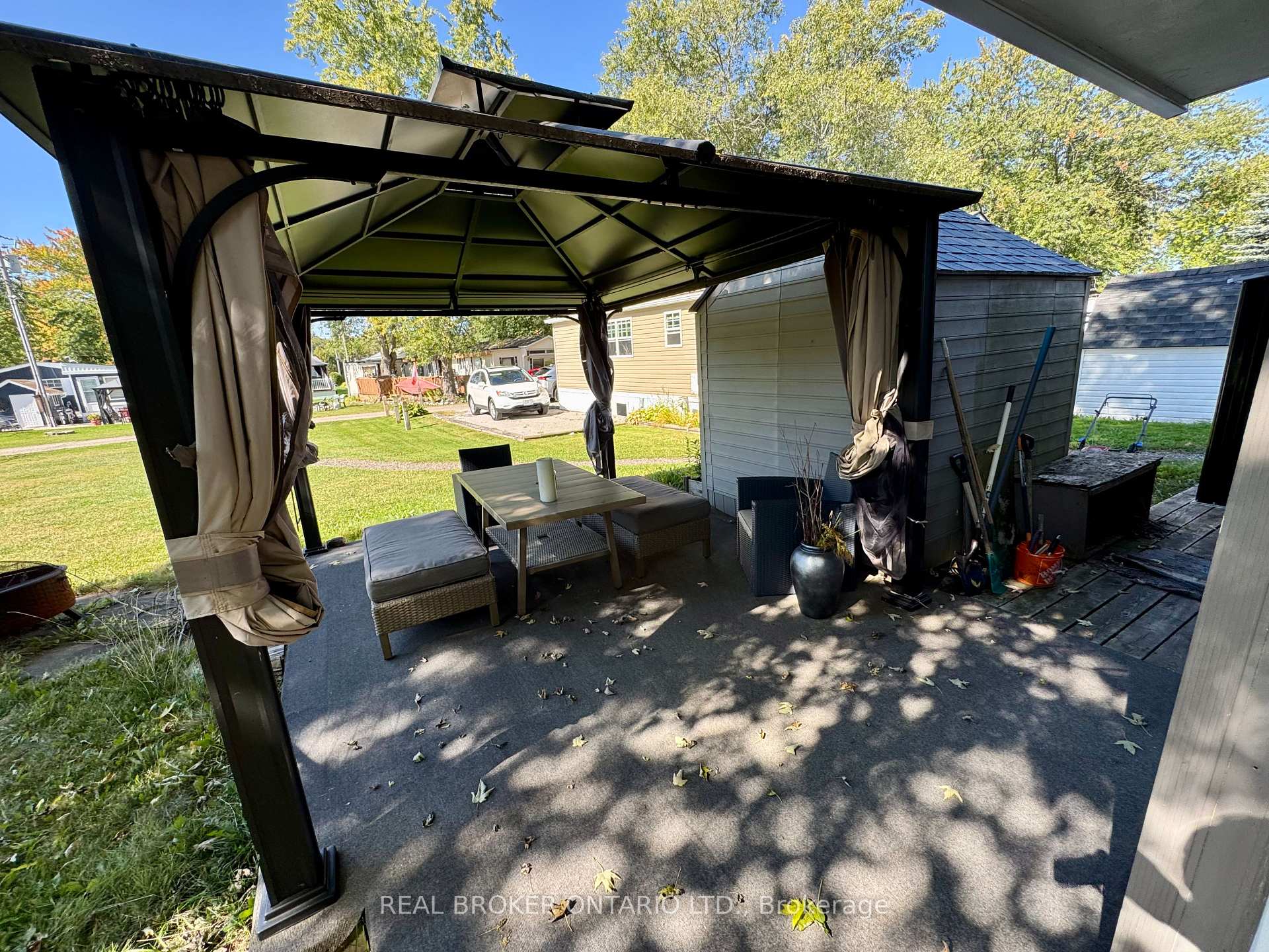 Covered patio with a metal gazebo, tied-back curtains, and wicker lounge seating.