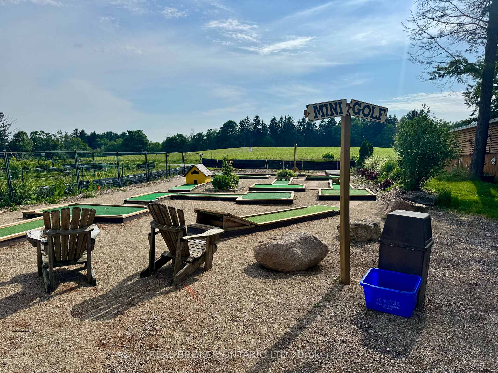 Outdoor mini-golf course with several putting lanes and wooden Adirondack chairs.