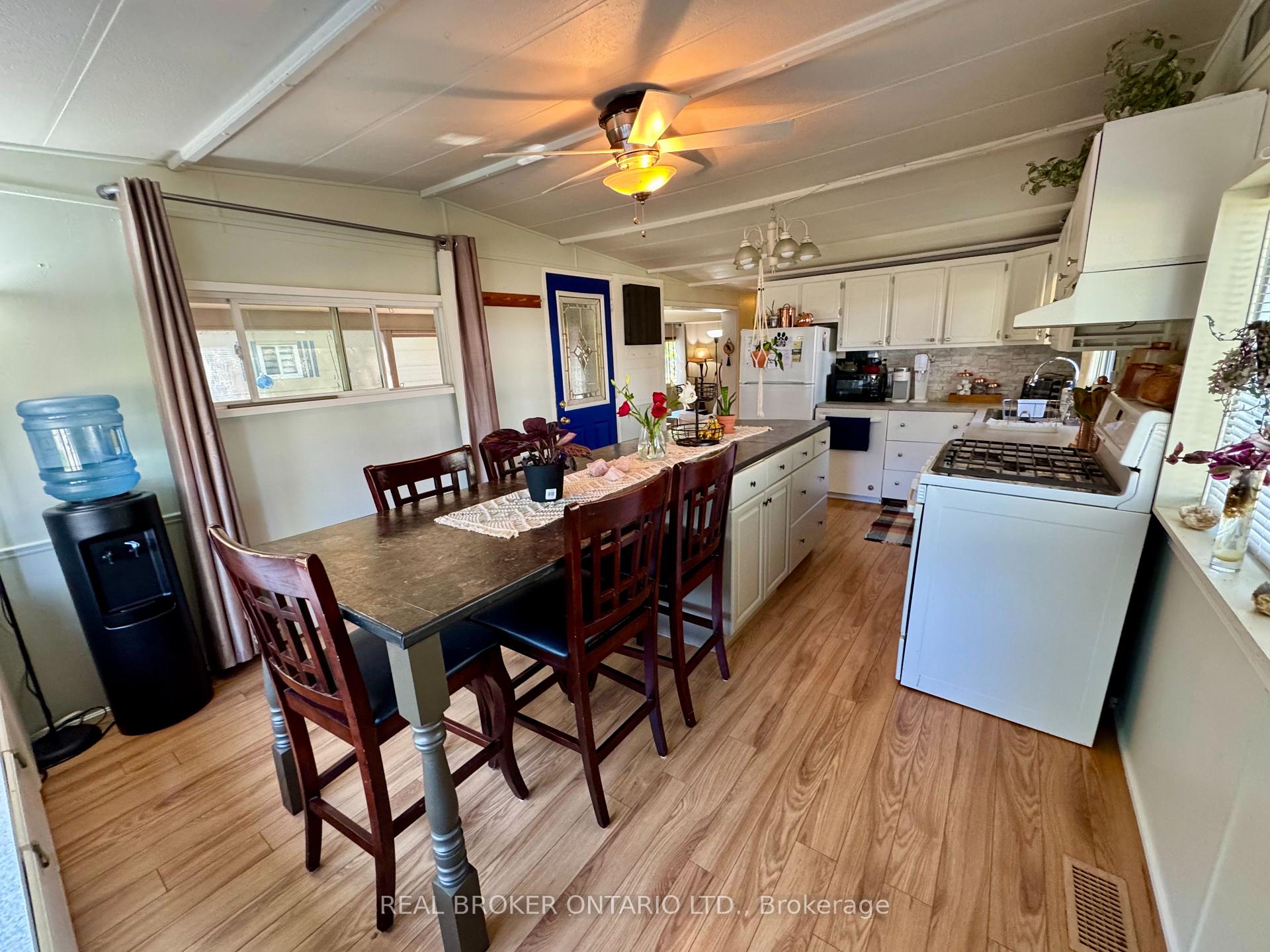 Kitchen with a dining island, wooden chairs, white cabinetry, and a large white range.