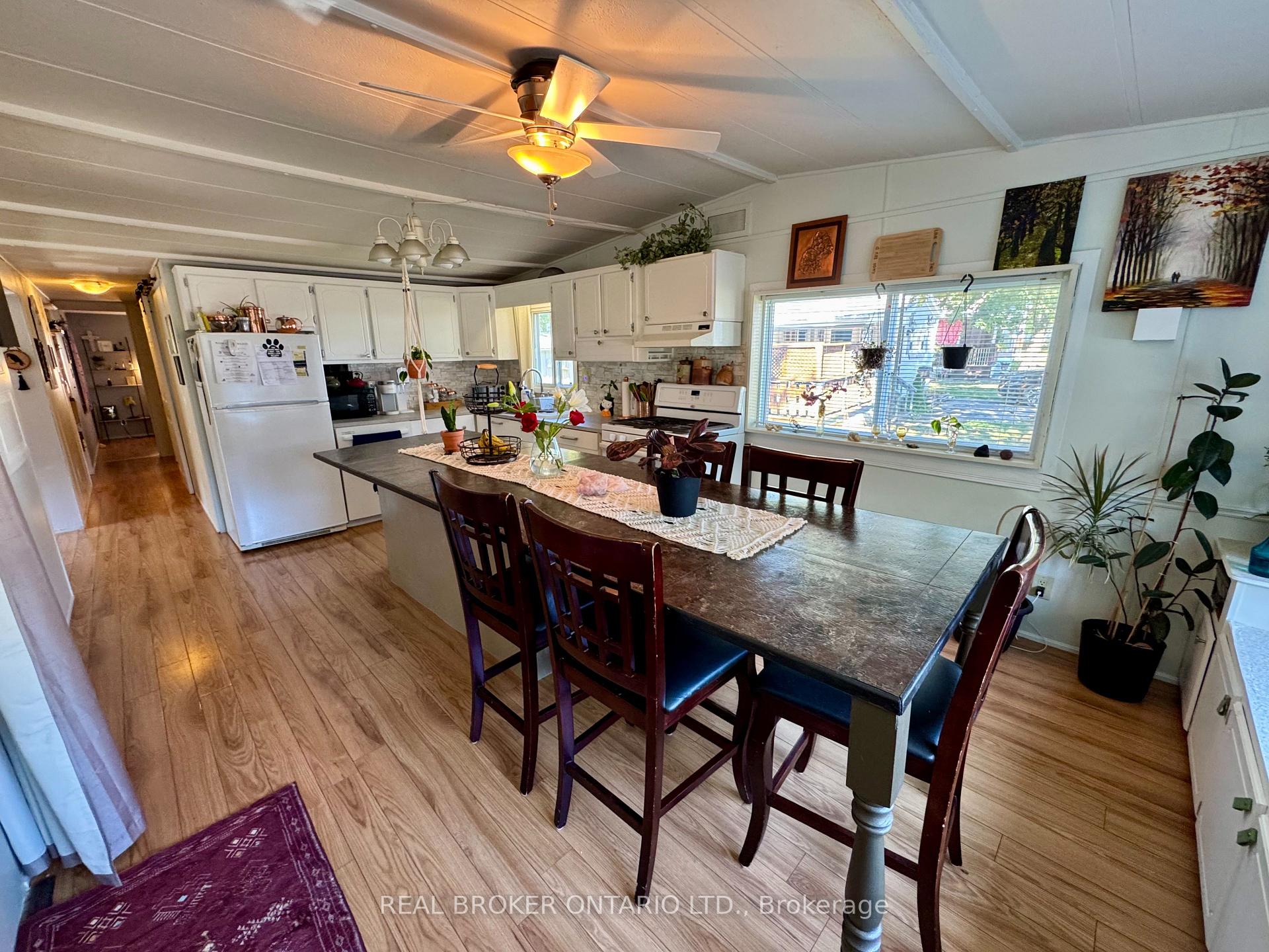 Kitchen and dining area with a large dark table, white cabinets, and a wide window.