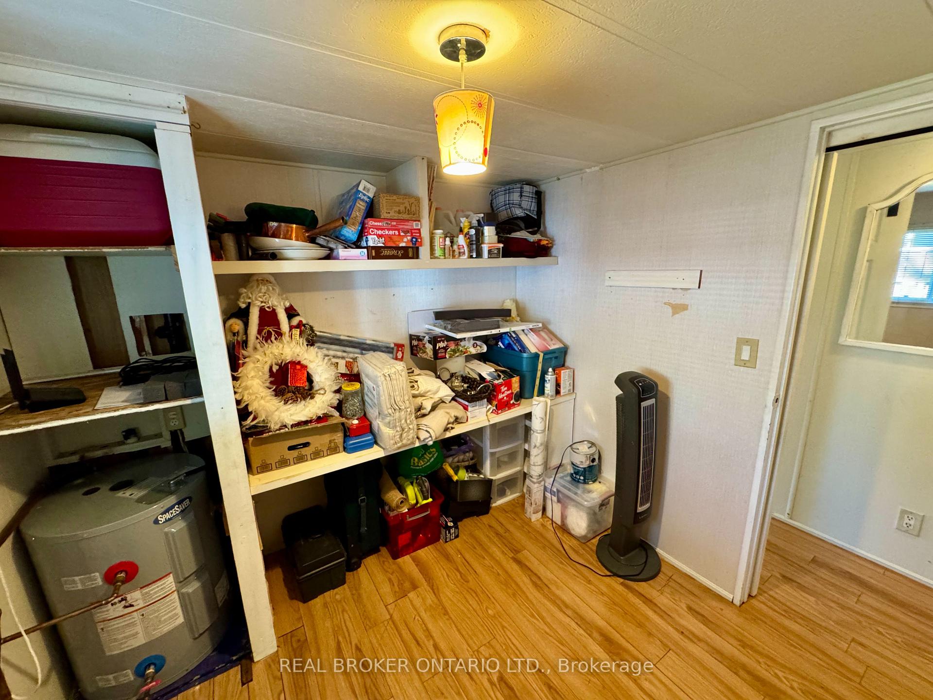 Storage room with packed open shelves, a water heater, and a tower fan.