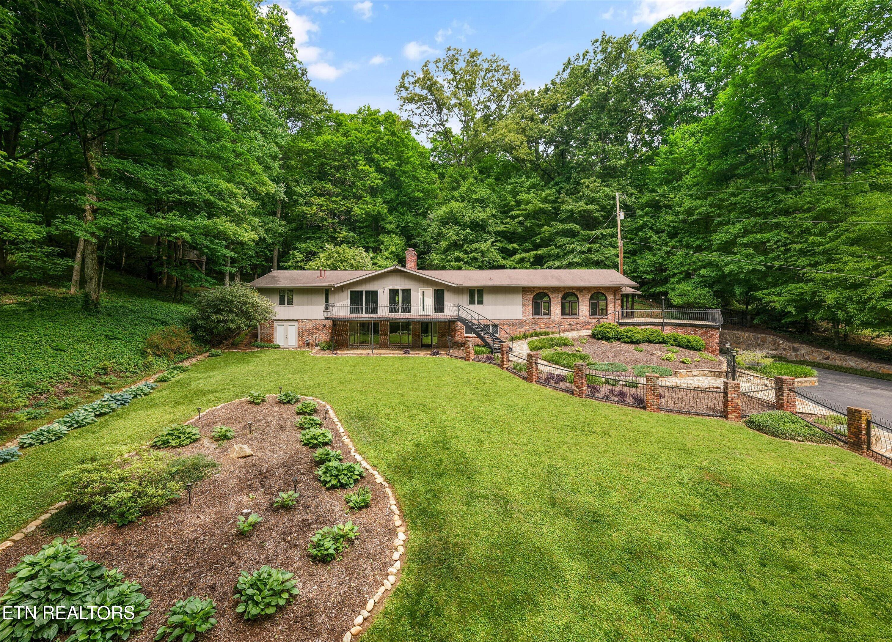 Wooded home with brick lower facade, elevated deck, and landscaped lawn.