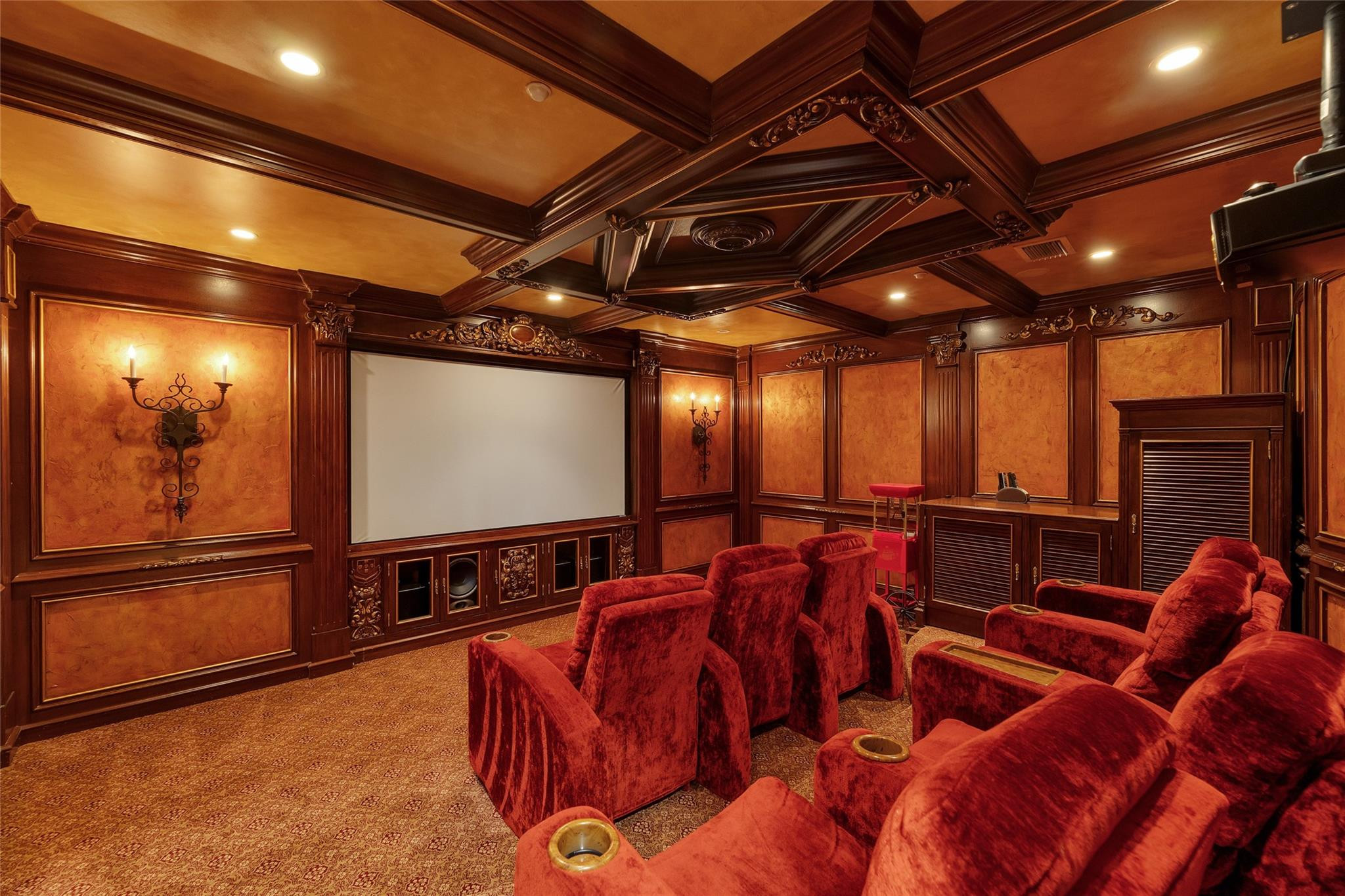 Home theater with red reclining seats, a large screen, and ornate dark wood paneling.