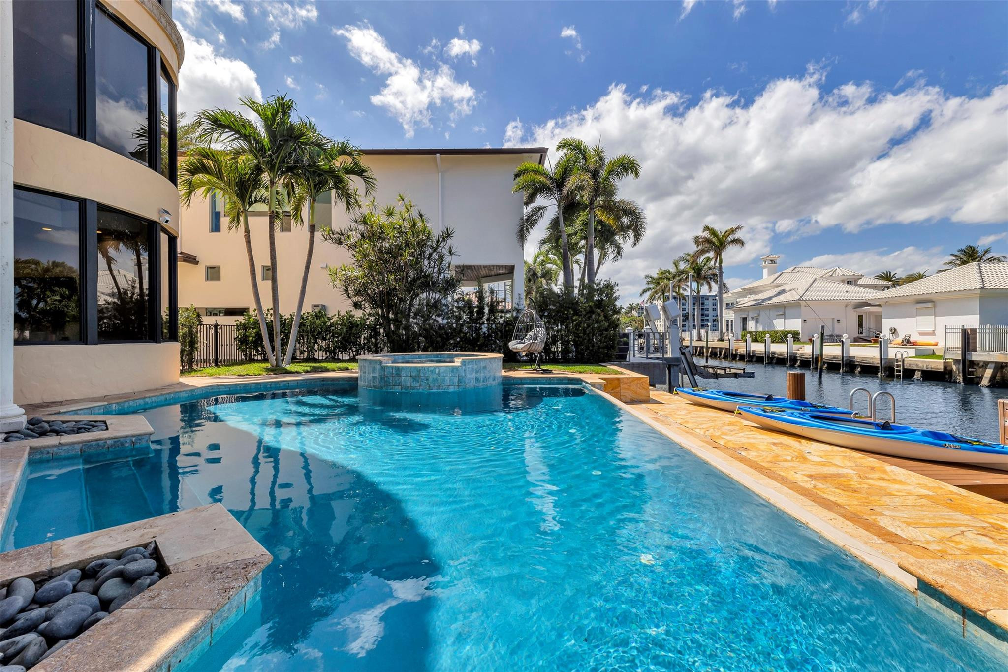 Waterfront home with a blue pool, raised spa, and kayaks beside the canal.