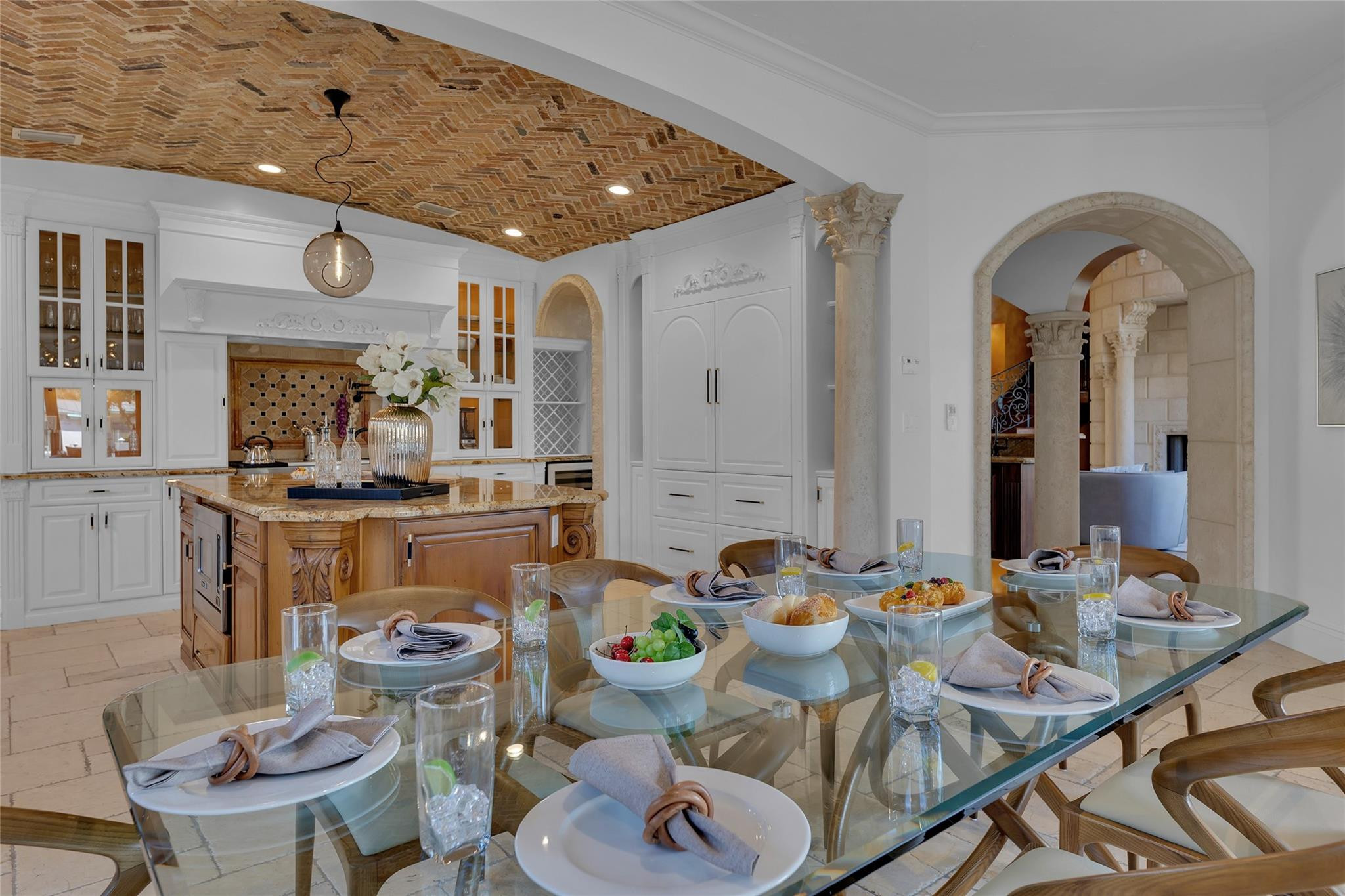 Kitchen and dining area with a brick ceiling, carved island, and set glass table.