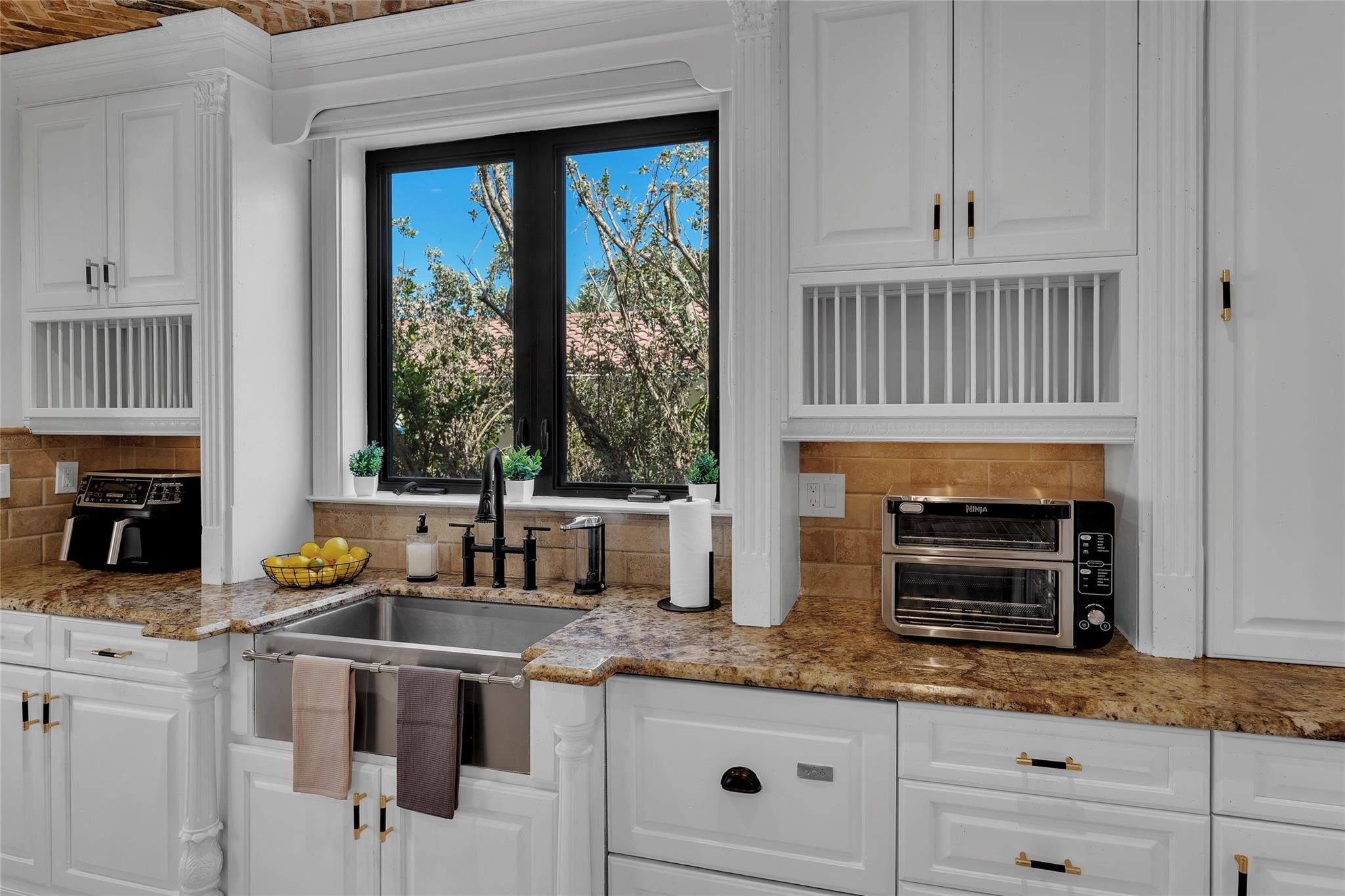 Kitchen with white cabinetry, granite counters, and a black-framed window above the sink.