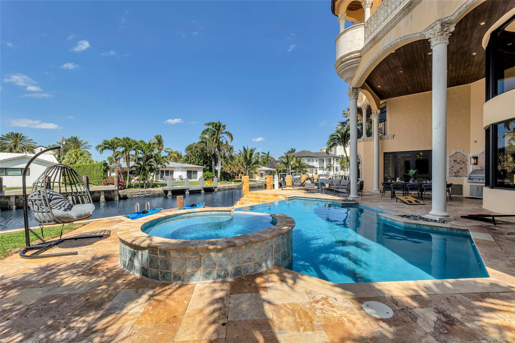 Backyard pool and raised spa beside a canal, with patio seating and an arched home exterior.