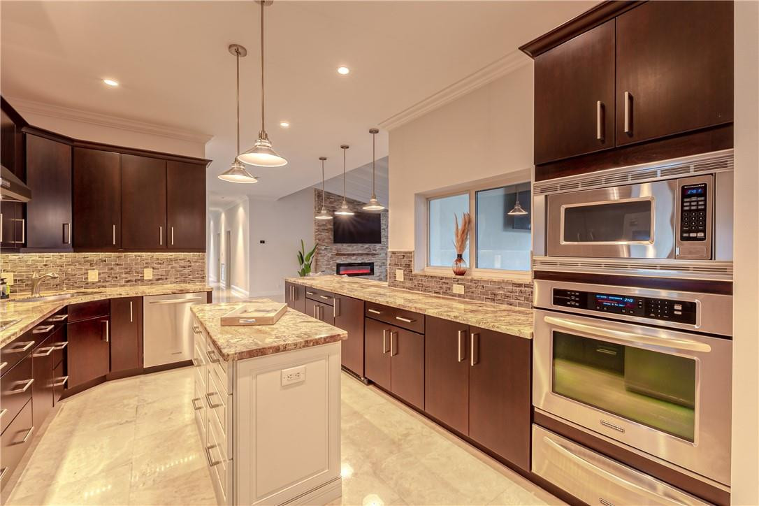 Kitchen with dark wood cabinets, granite island, and stainless steel appliances.